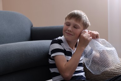 Boy popping bubble wrap at home. Stress relief