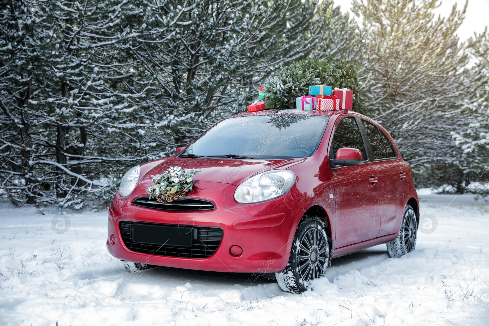 Photo of Car with Christmas tree, wreath and gifts in snowy forest on winter day