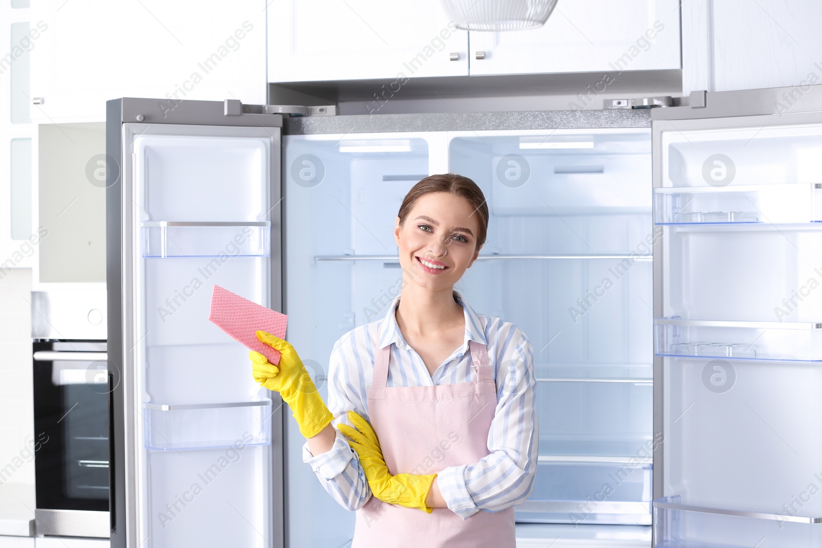 Photo of Woman with rag near clean refrigerator at home