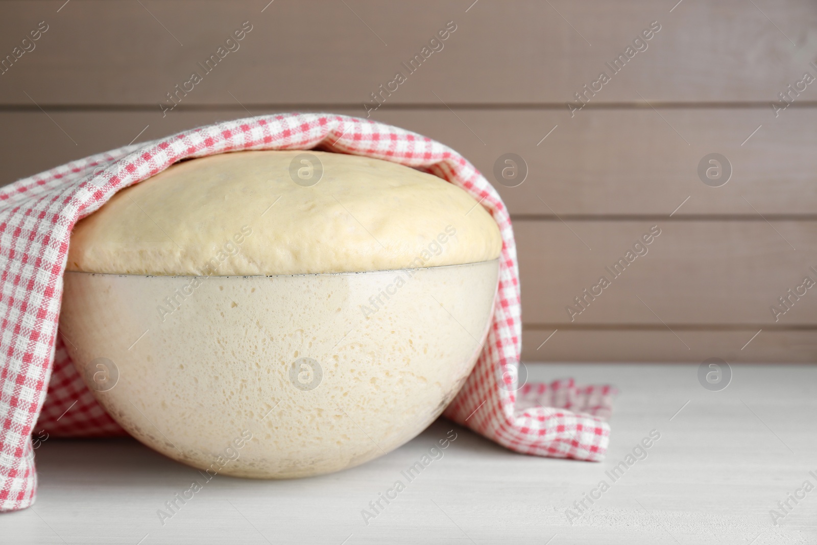 Photo of Bowl of fresh yeast dough on white wooden table. Space for text