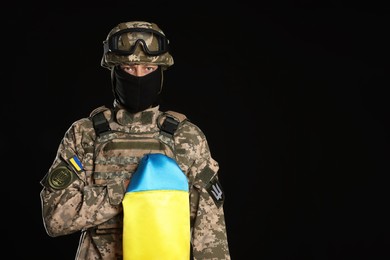Photo of Soldier in military uniform with Ukrainian flag on black background. Space for text