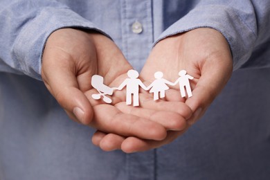 Photo of Man holding paper family figures, closeup. Insurance concept