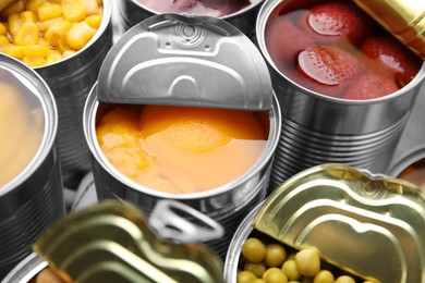 Photo of Open tin cans with different products, closeup