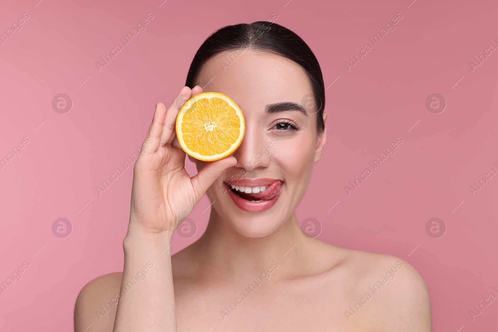 Photo of Beautiful young woman with piece of orange on pink background