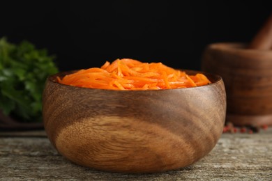 Photo of Delicious Korean carrot salad in bowl on wooden table