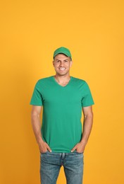 Photo of Happy man in green cap and tshirt on yellow background. Mockup for design