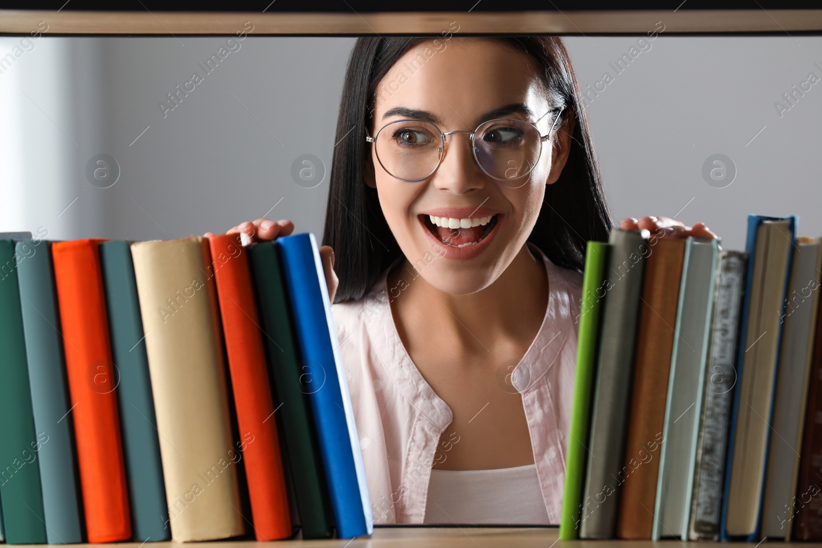 Photo of Woman searching for book on shelf in library