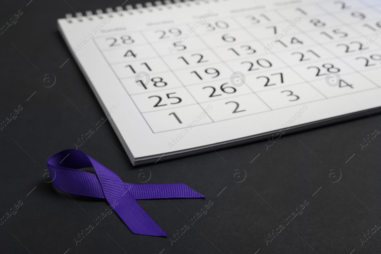 Photo of Purple awareness ribbon and calendar on black background