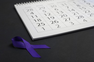 Purple awareness ribbon and calendar on black background