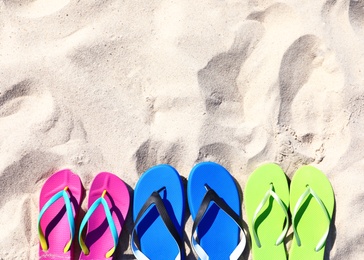 Photo of Flat lay composition with flip flops on sand in summer, space for text. Beach accessories