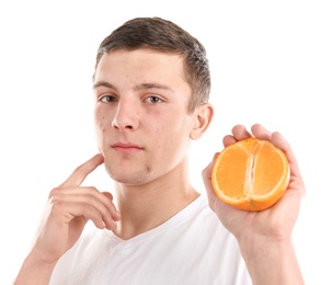 Young man with acne problem holding orange on white background. Skin allergy