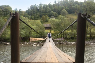 Photo of Young woman walking on wooden bridge over river