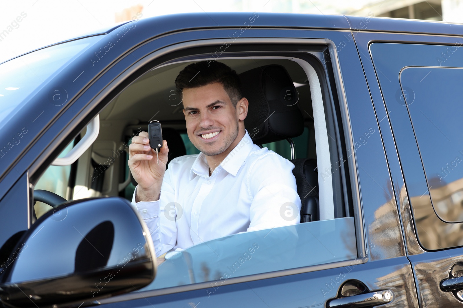 Photo of Man with key sitting in car outdoors. Buying new auto