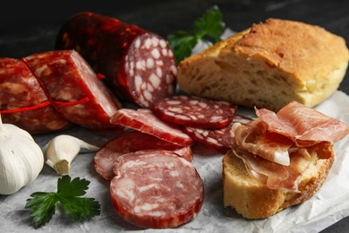 Different types of sausages and bread on parchment paper, closeup