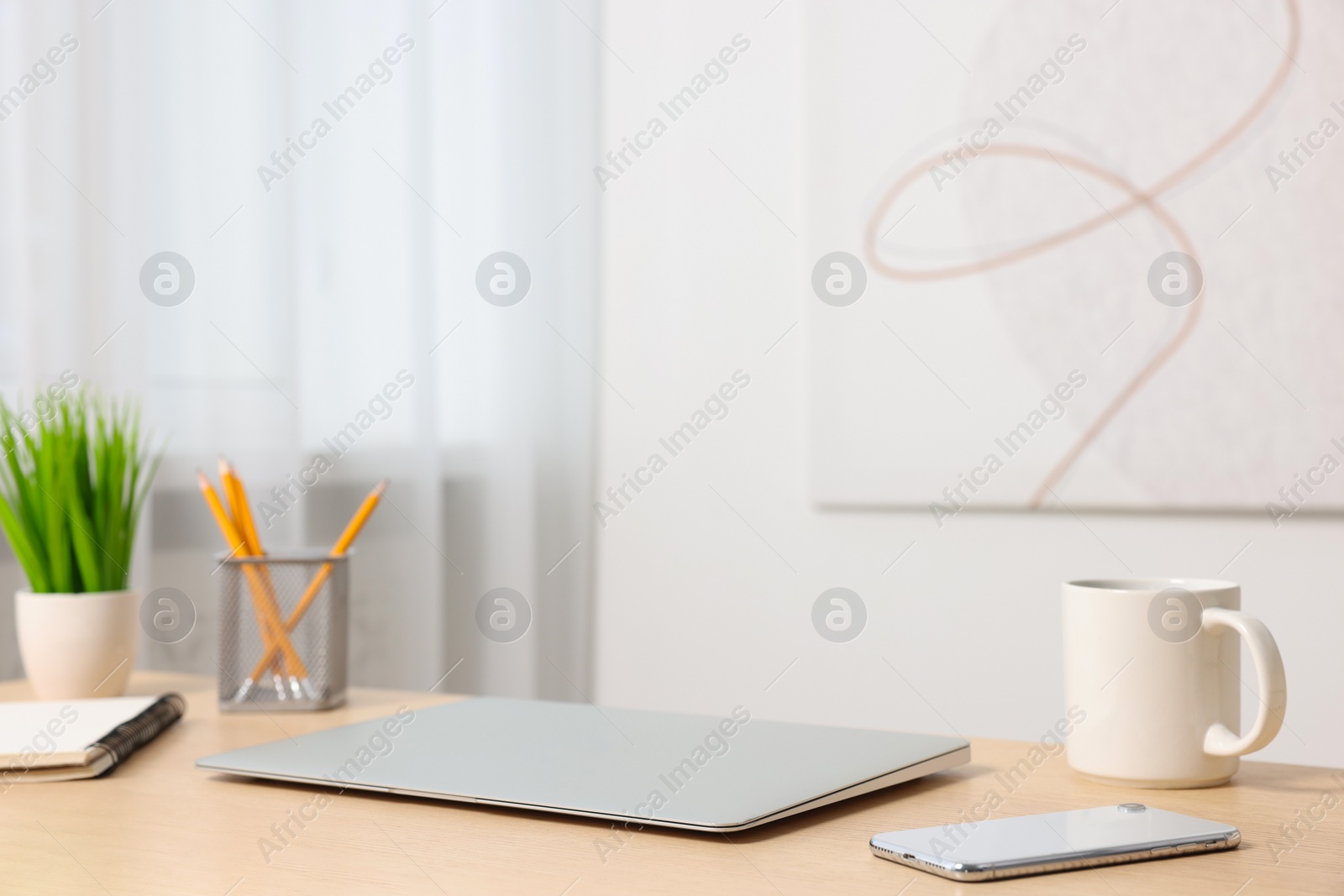 Photo of Home office. Laptop, smartphone, cup and stationery on wooden desk indoors. Space for text