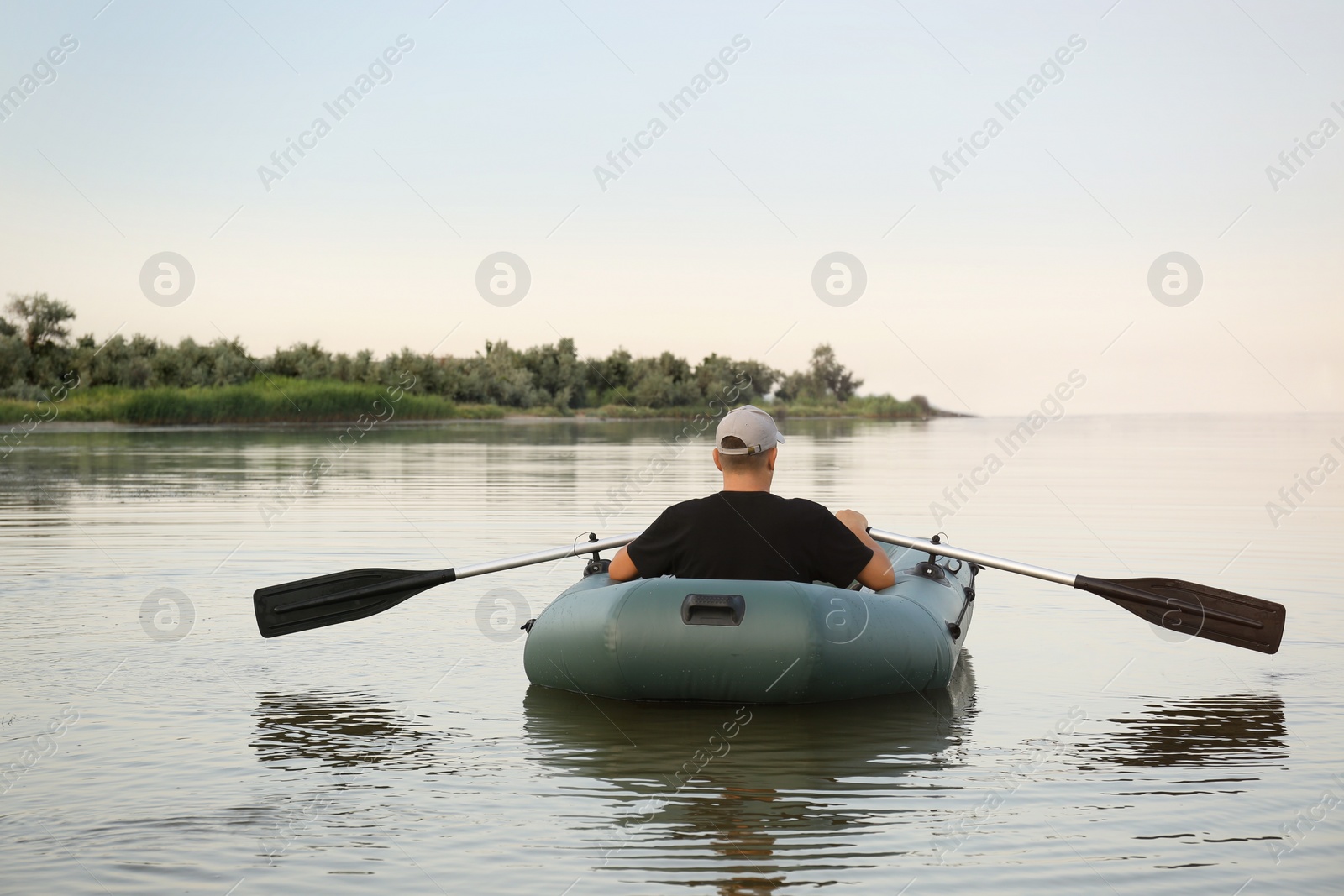 Photo of Man rowing inflatable rubber fishing boat on river, back view