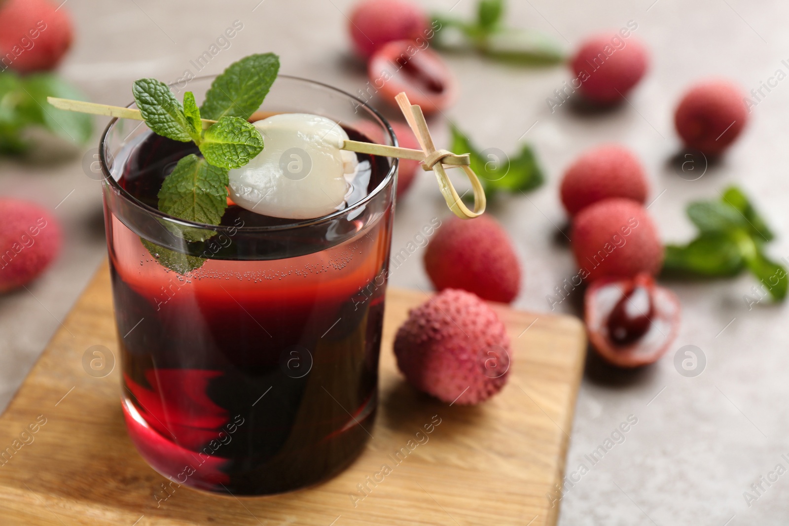 Photo of Lychee cocktail with mint and fresh fruits on grey table, closeup. Space for text