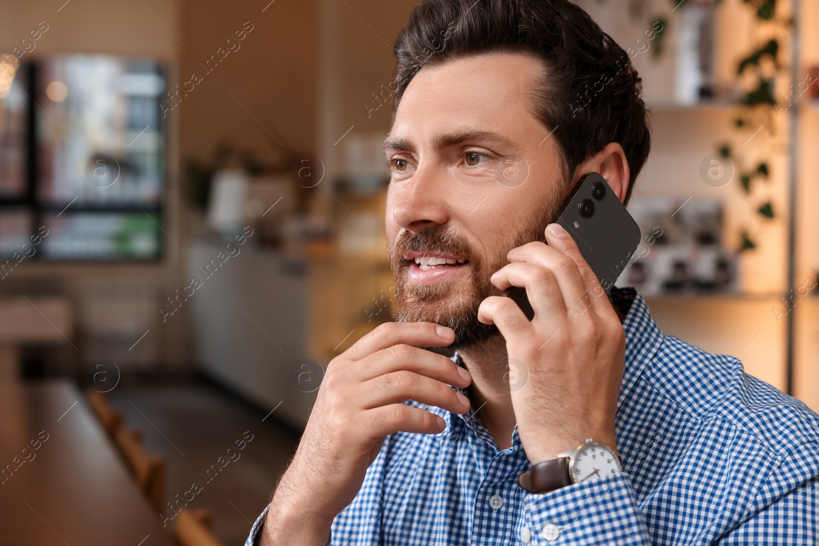 Photo of Handsome man talking on phone in cafe