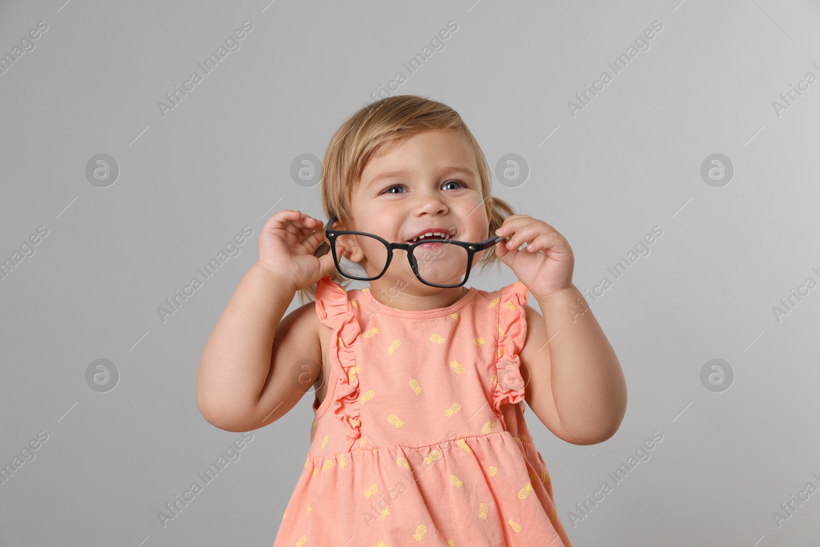 Photo of Cute little girl with glasses on light grey background