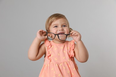 Cute little girl with glasses on light grey background