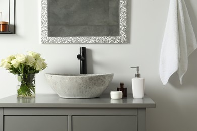 Photo of Vase with beautiful white roses and toiletries near sink in bathroom