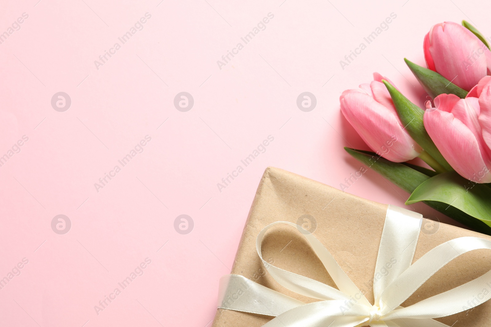 Photo of Happy Mother's Day. Beautiful tulips and gift box on pink background, flat lay. Space for text