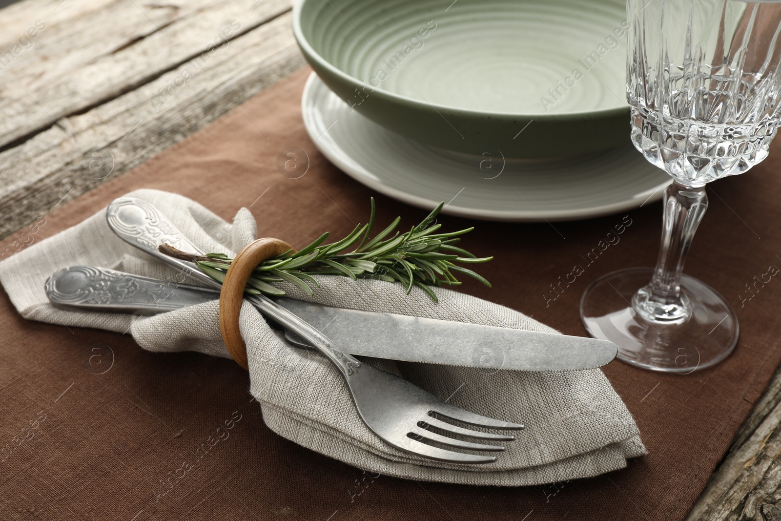 Photo of Stylish setting with cutlery, glass and plate on wooden table, closeup