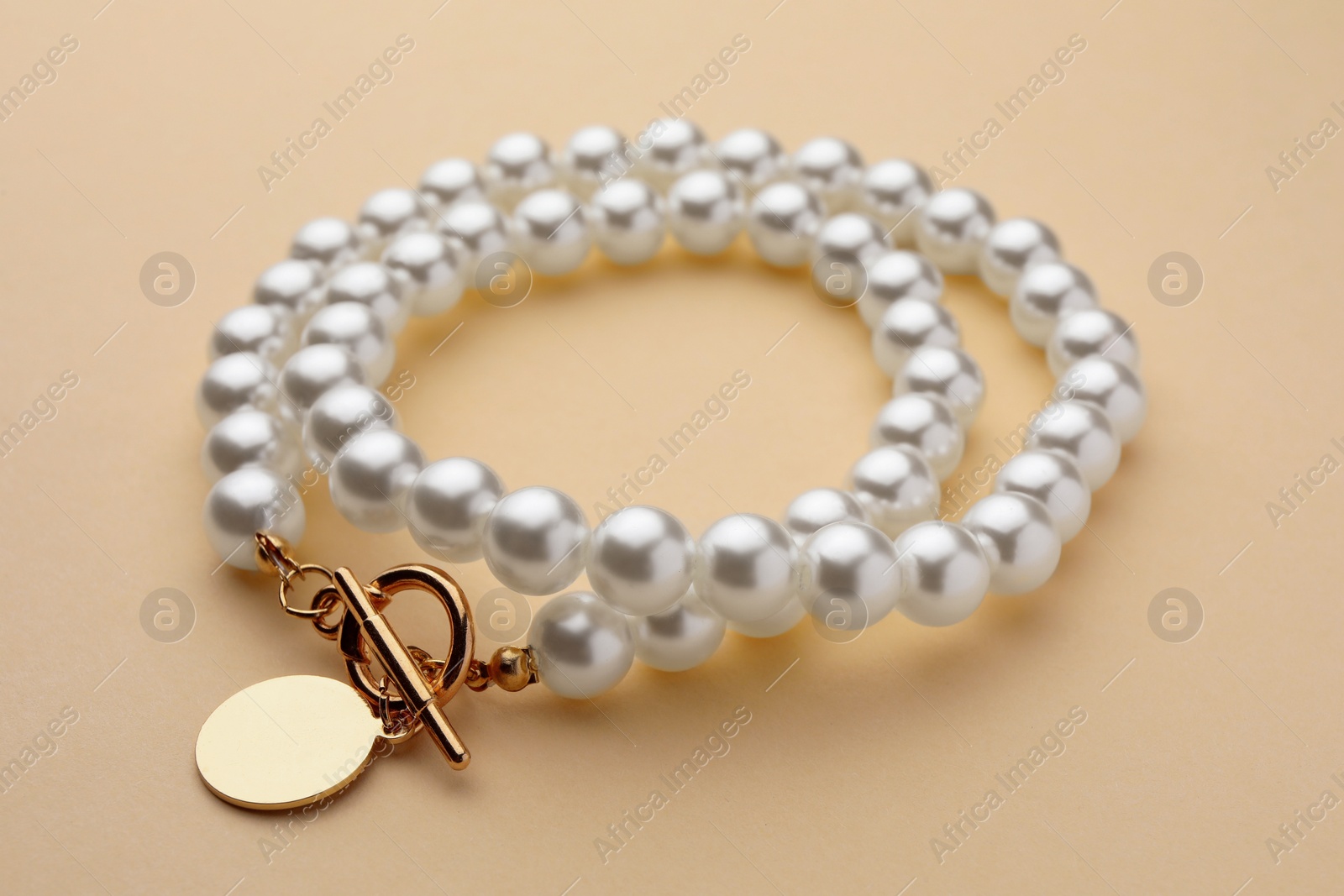 Photo of Elegant necklace with pearls on beige background