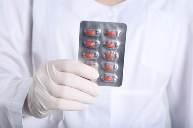 Doctor holding red pills, closeup. Anemia treatment