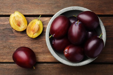 Photo of Tasty ripe plums on wooden table, flat lay