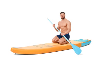 Photo of Handsome man with paddle on orange SUP board against white background