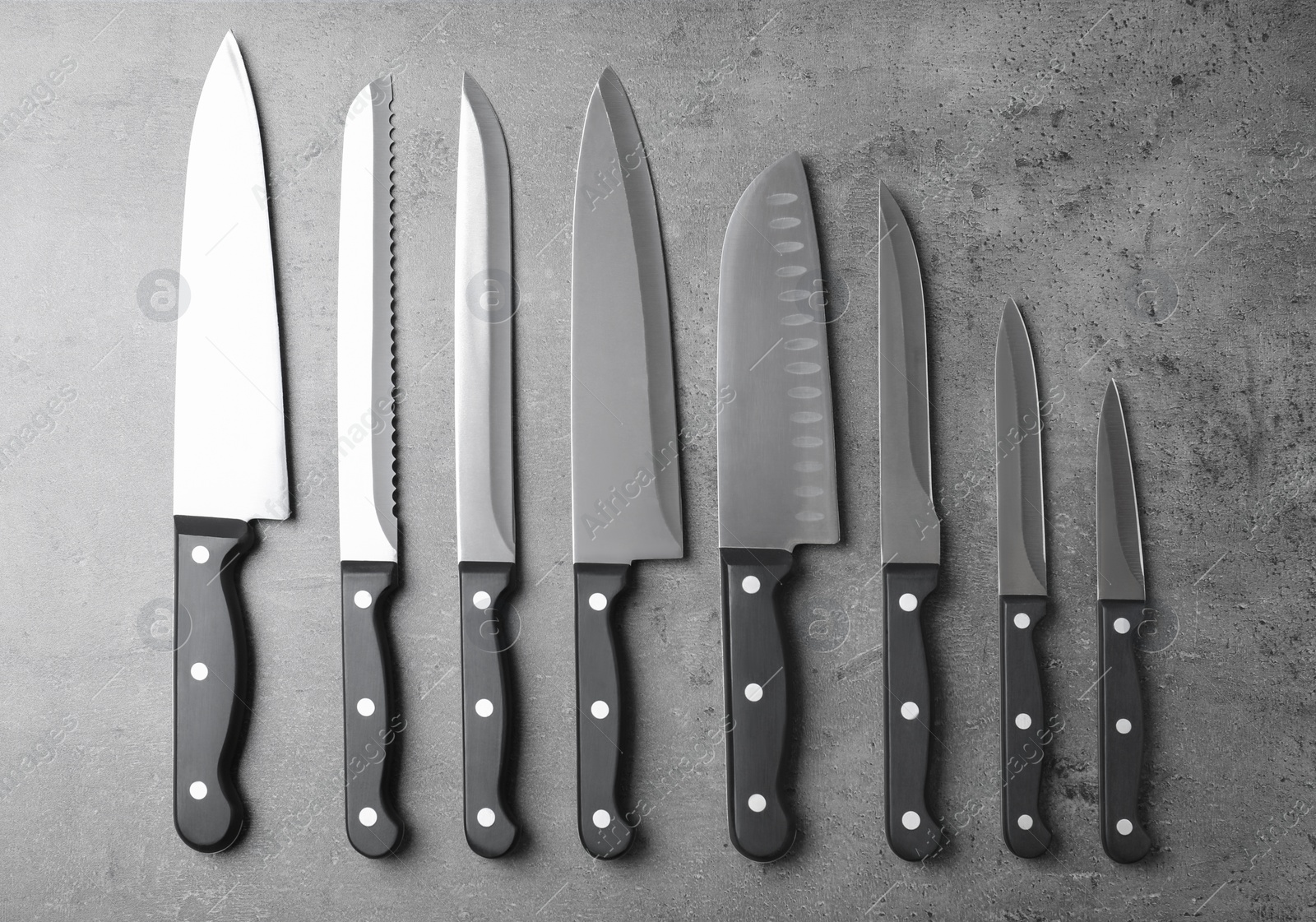 Photo of Set of sharp knives on grey background, flat lay