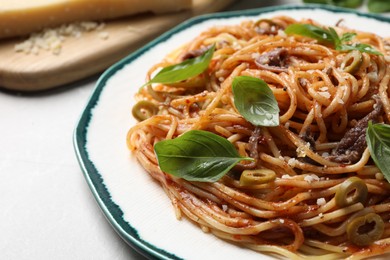 Photo of Delicious pasta with anchovies, tomato sauce and basil on white table, closeup