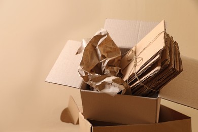 Heap of waste paper near beige wall, space for text