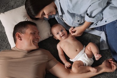 Photo of Happy family with their cute baby on floor, top view