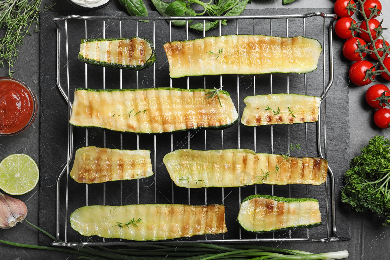 Photo of Flat lay composition with delicious grilled zucchini slices on grey table