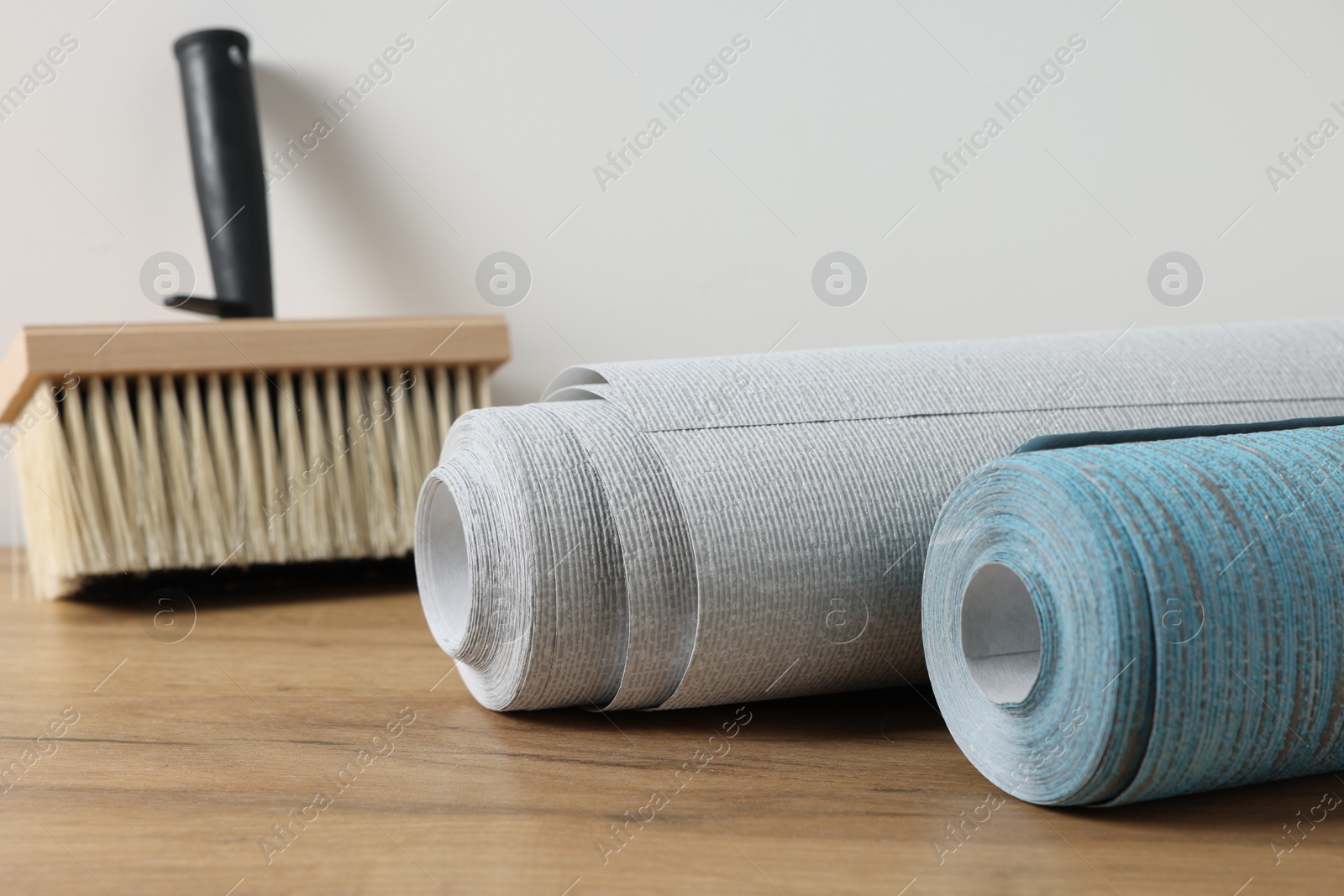 Photo of Wallpaper rolls and brush on wooden table