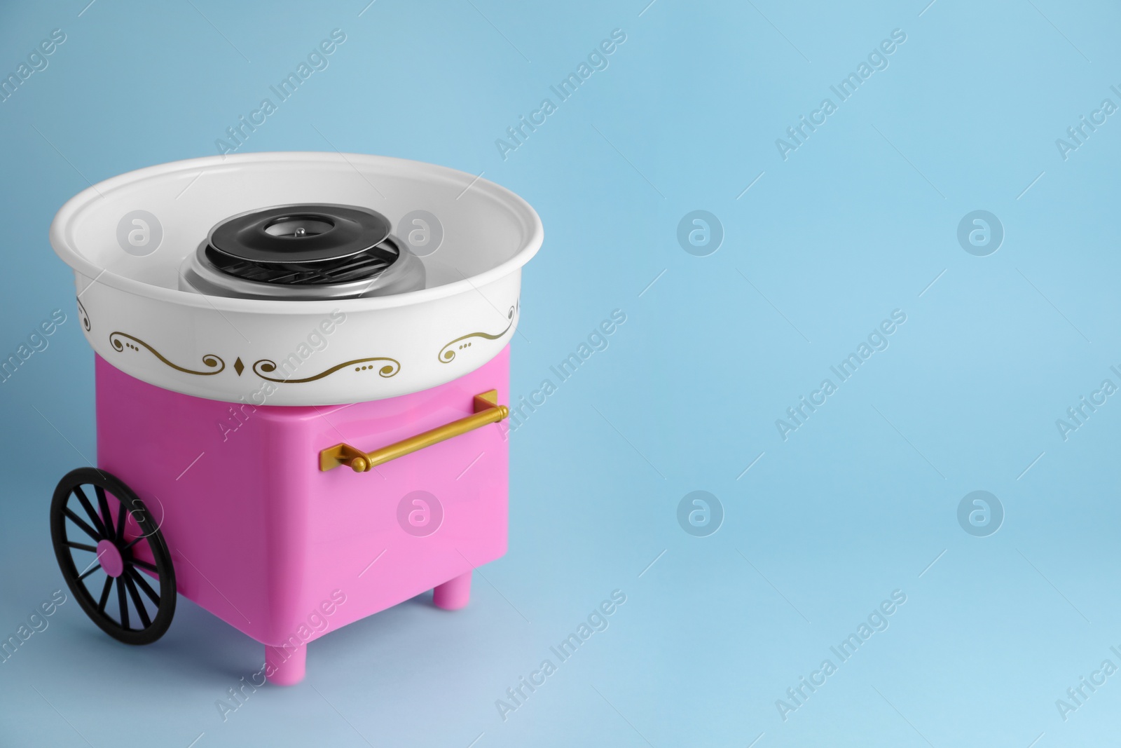 Photo of Portable candy cotton machine on light blue background, space for text