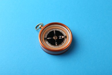 Photo of One compass on light blue background. Tourist equipment
