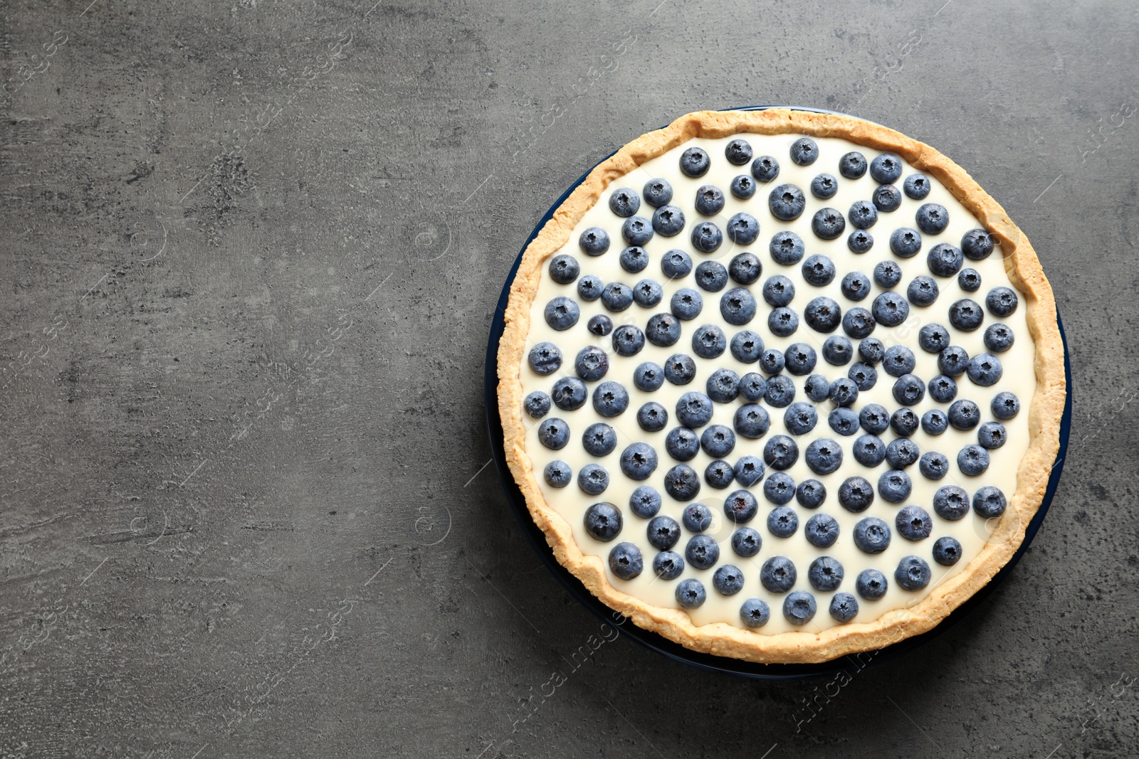 Photo of Tasty blueberry cake on gray background, top view with space for text