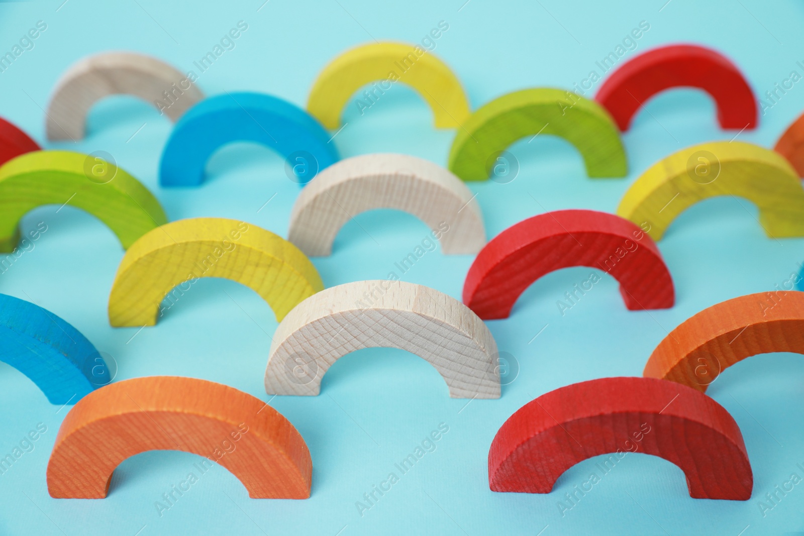 Photo of Colorful wooden pieces of playing set on light blue background. Educational toy for motor skills development