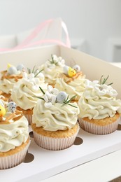 Photo of Tasty Easter cupcakes with vanilla cream in box, closeup