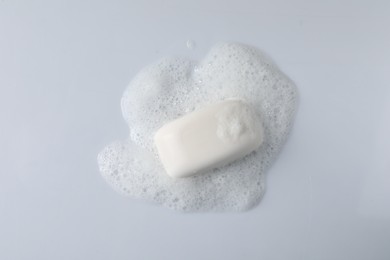 Soap with fluffy foam on white background, top view