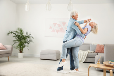 Happy mature couple dancing together in living room