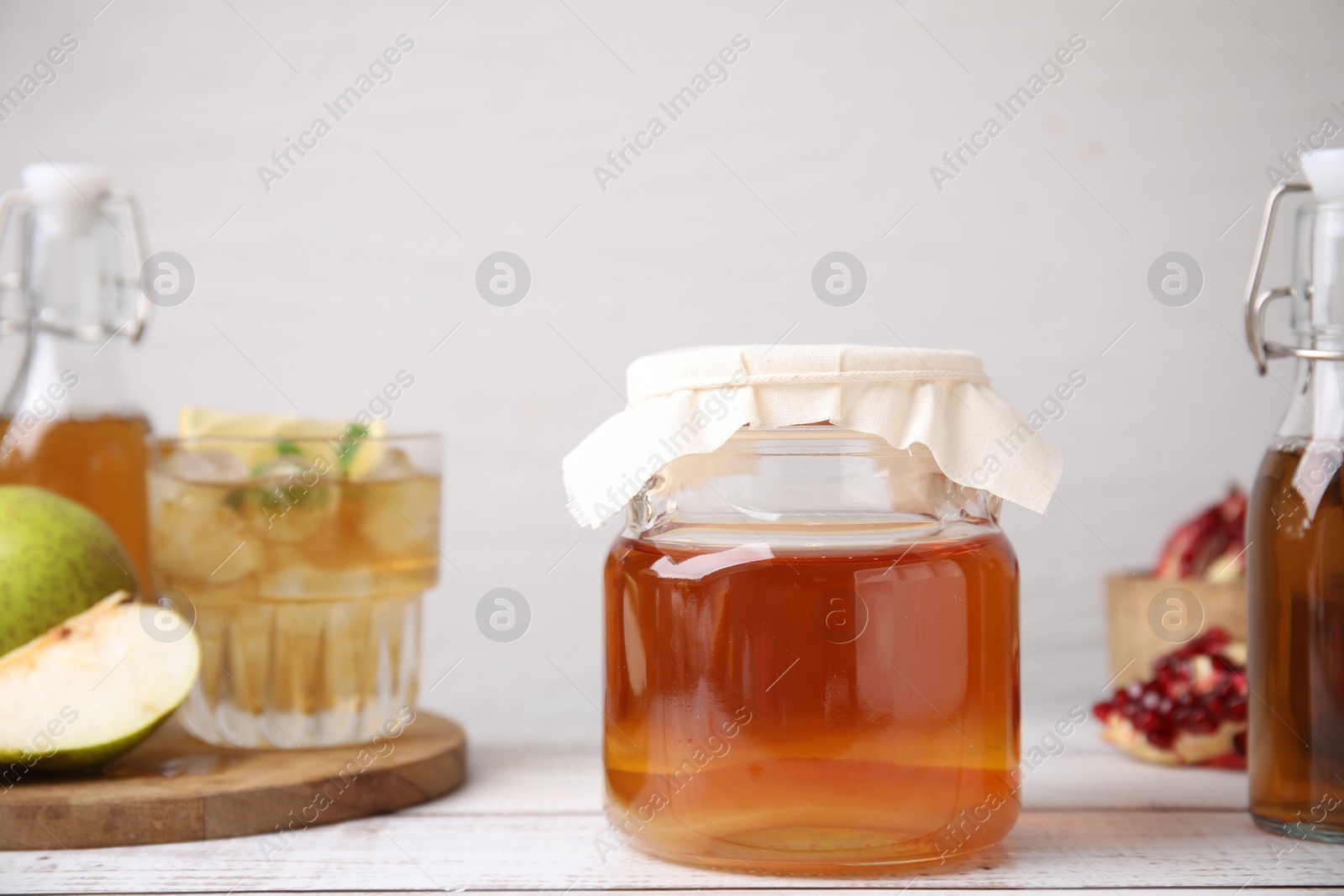 Photo of Tasty kombucha and fruits on white wooden table