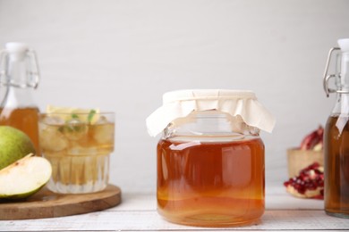 Photo of Tasty kombucha and fruits on white wooden table