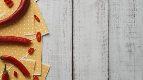 Photo of Pepper plasters and chili on white wooden table, flat lay. Space for text