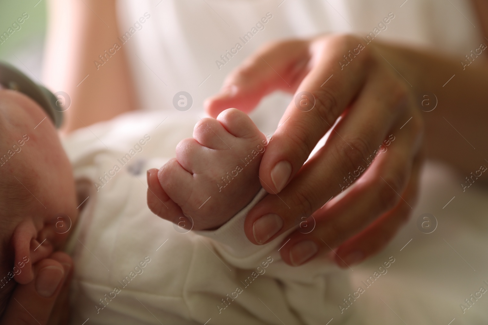 Photo of Mother with newborn baby indoors, focus on hands