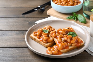 Photo of Toasts with delicious canned beans on wooden table