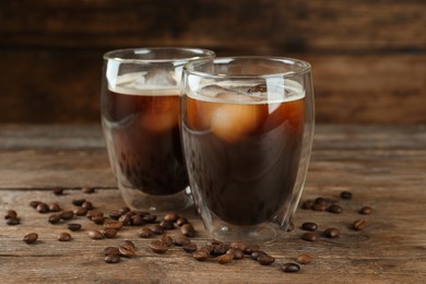 Photo of Glasses of delicious iced coffee served on wooden table